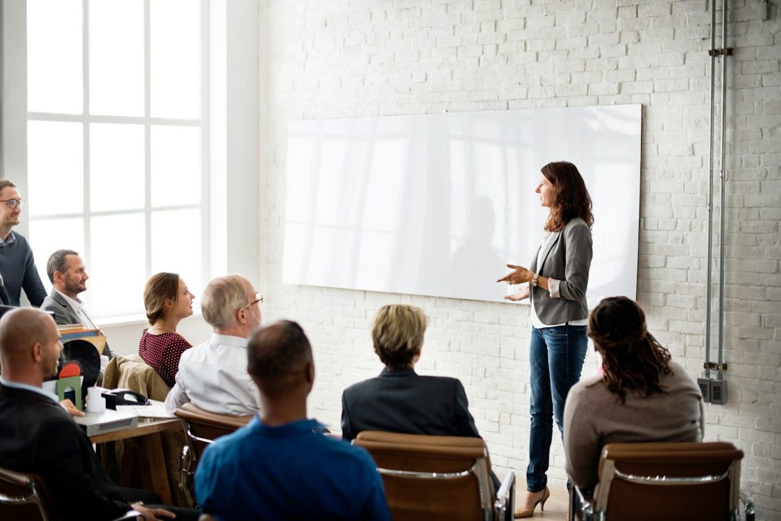 A woman presents to an audience in a modern conference room.